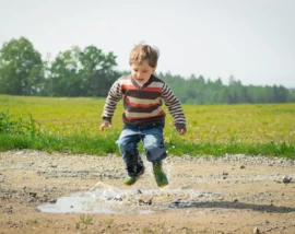 Little boy jumping in puddle